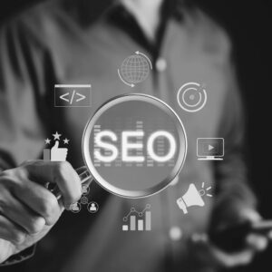 Business professional holding magnifying glass over SEO text with digital marketing icons floating around